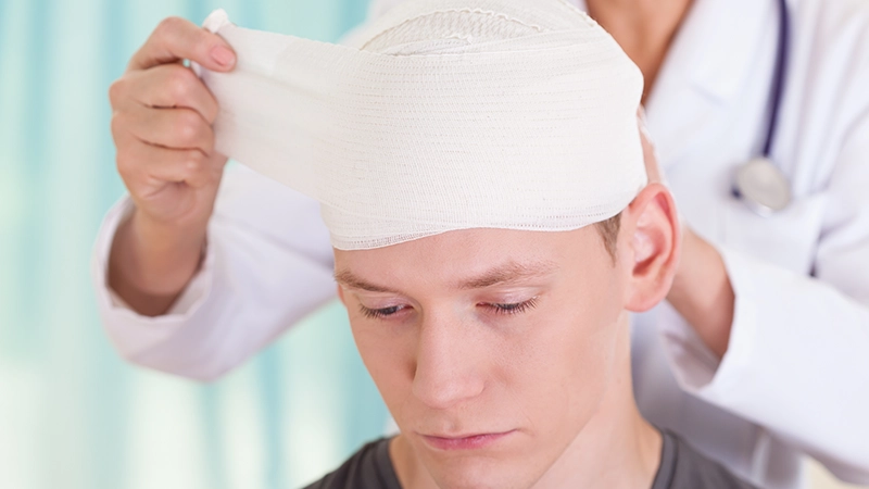 A doctor applying a bandage to a young man's head.